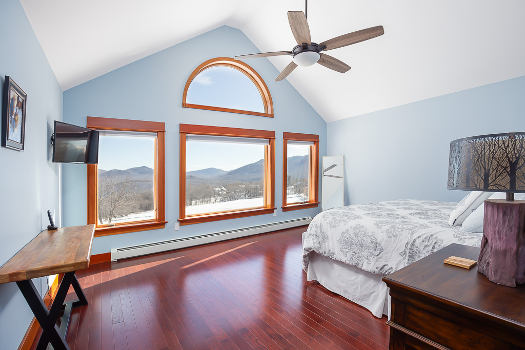 Primary bedroom with cathedral ceiling, arched window, and panoramic Green Mountain views