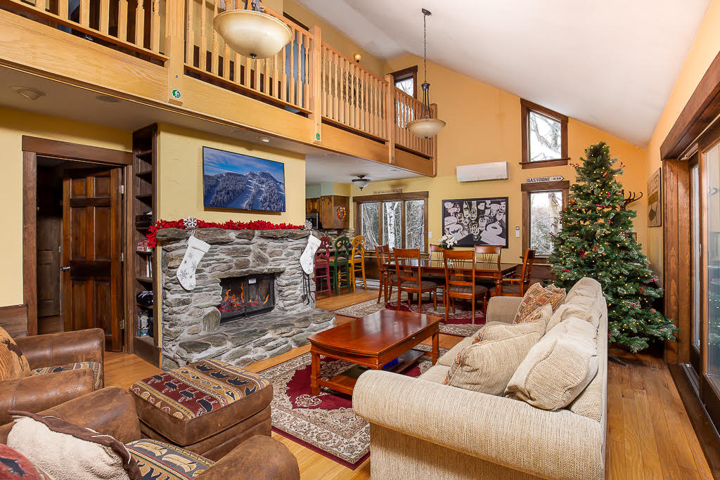 Great room with stone fireplace, vaulted ceiling, and decorated Christmas tree