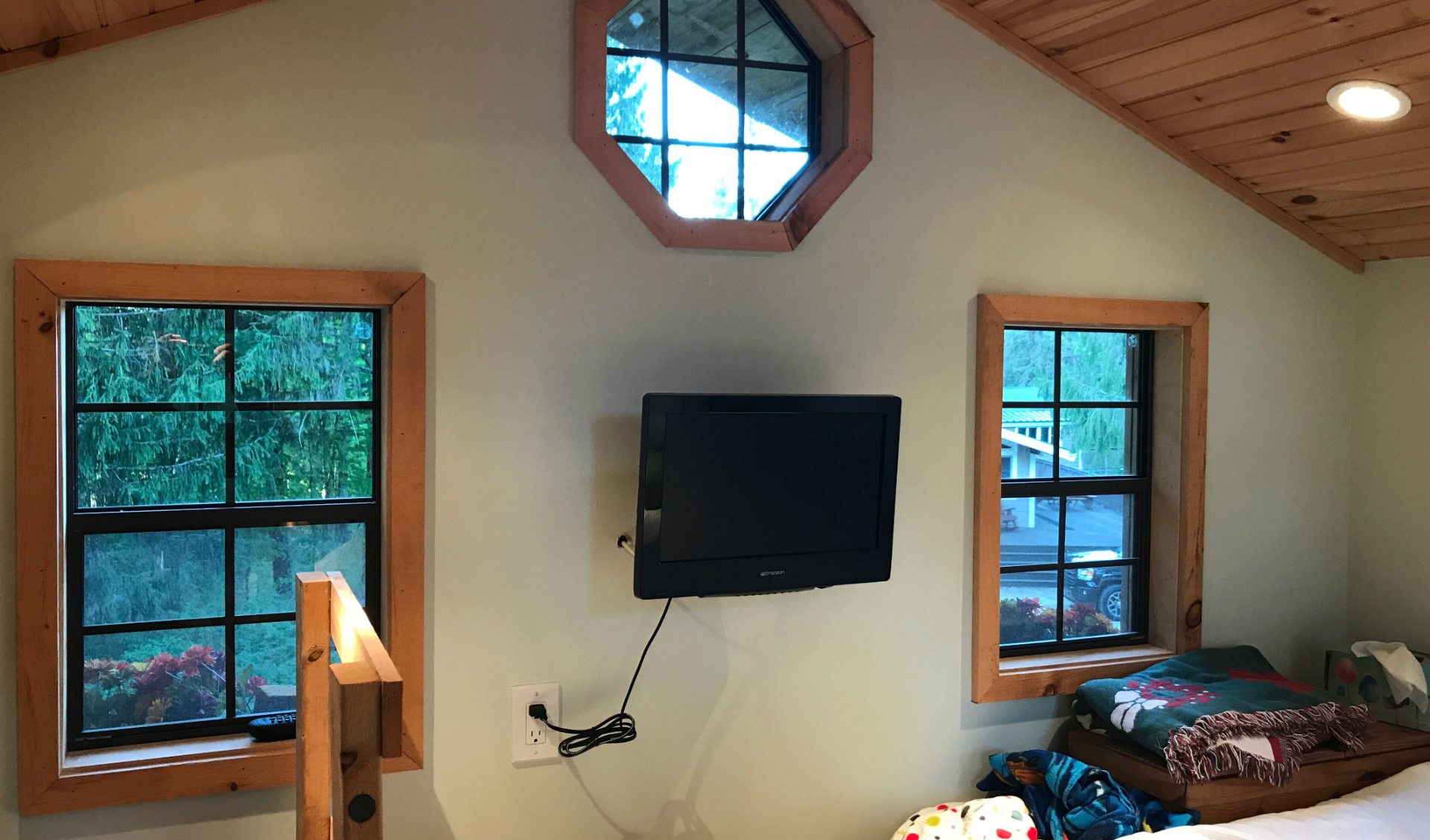Treehouse loft with octagonal window, wall-mounted TV, and forest views