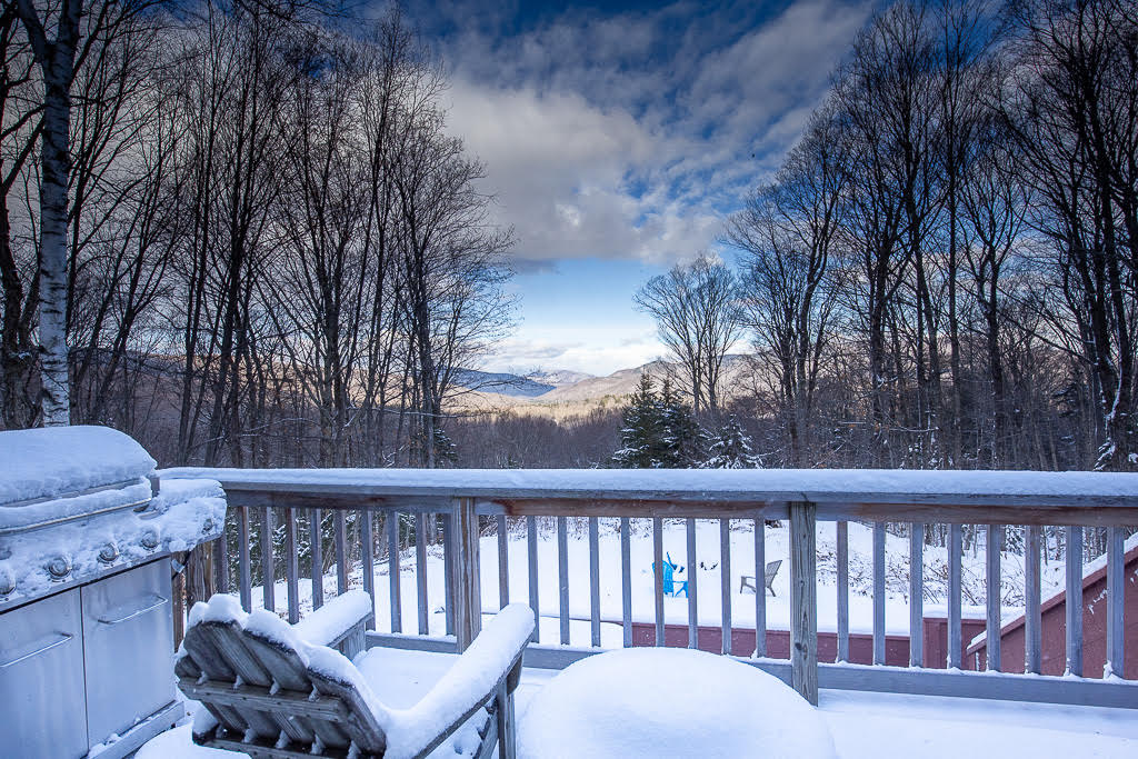 Snowy deck with mountain views and Adirondack chairs