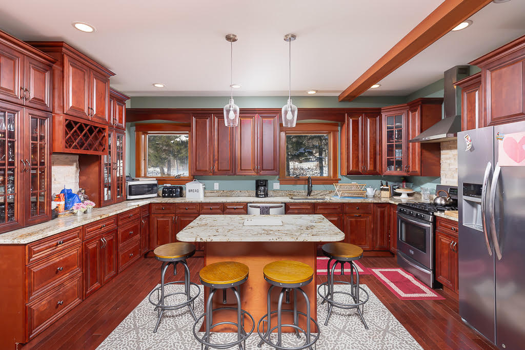 Cherry-wood chef's kitchen with granite island, gas range, and bar stool seating