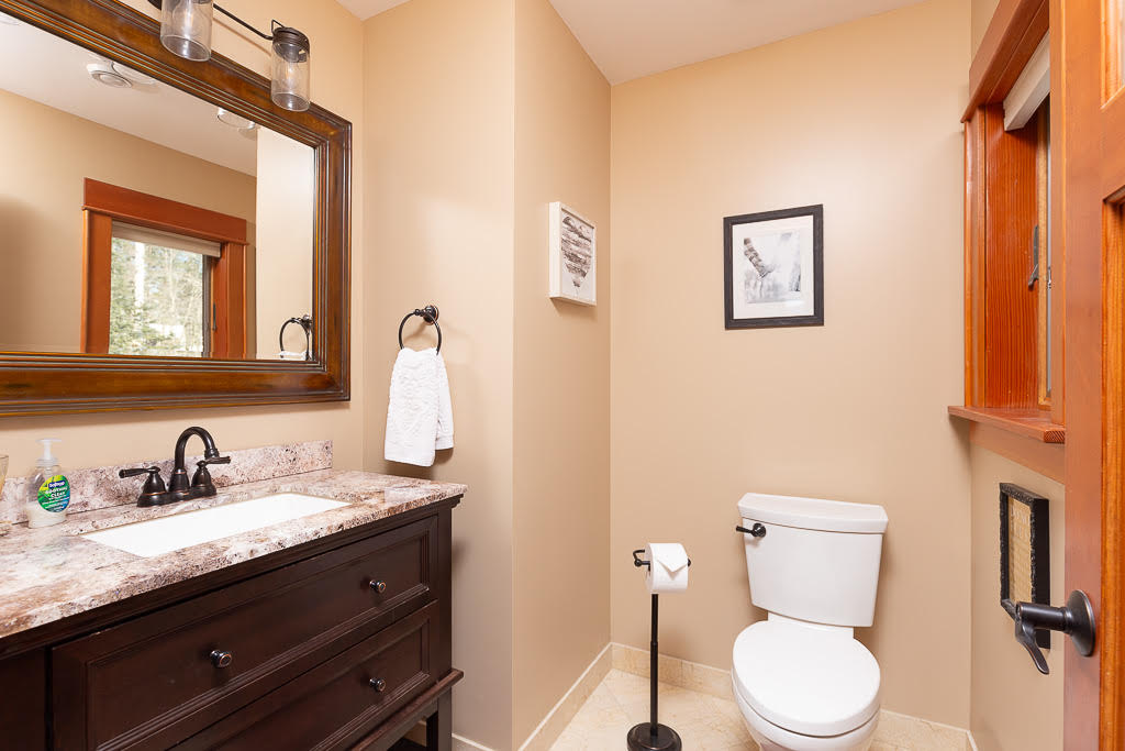 Powder room with granite vanity, dark cabinetry, and forest-view window