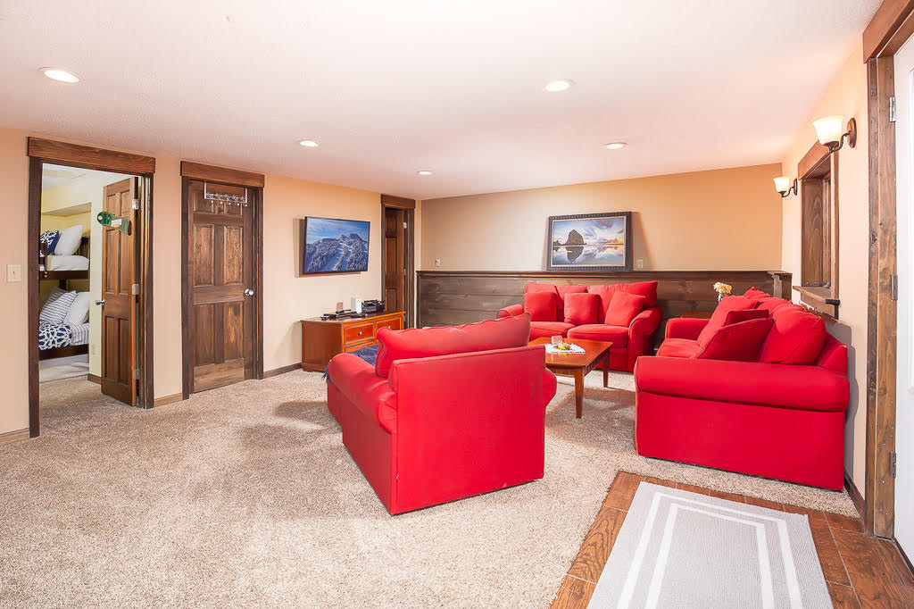 Lower-level rec room with red sofas, coffee table, and bunk room access