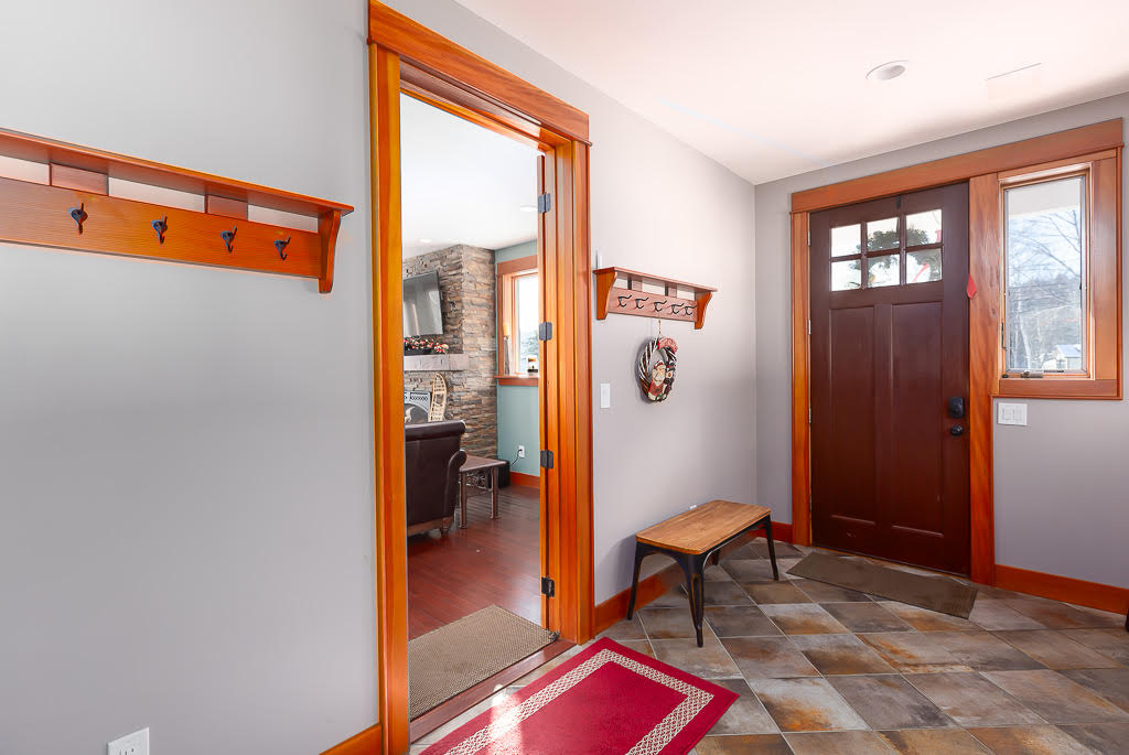 Front entry foyer with craftsman door, coat hooks, and slate tile floor