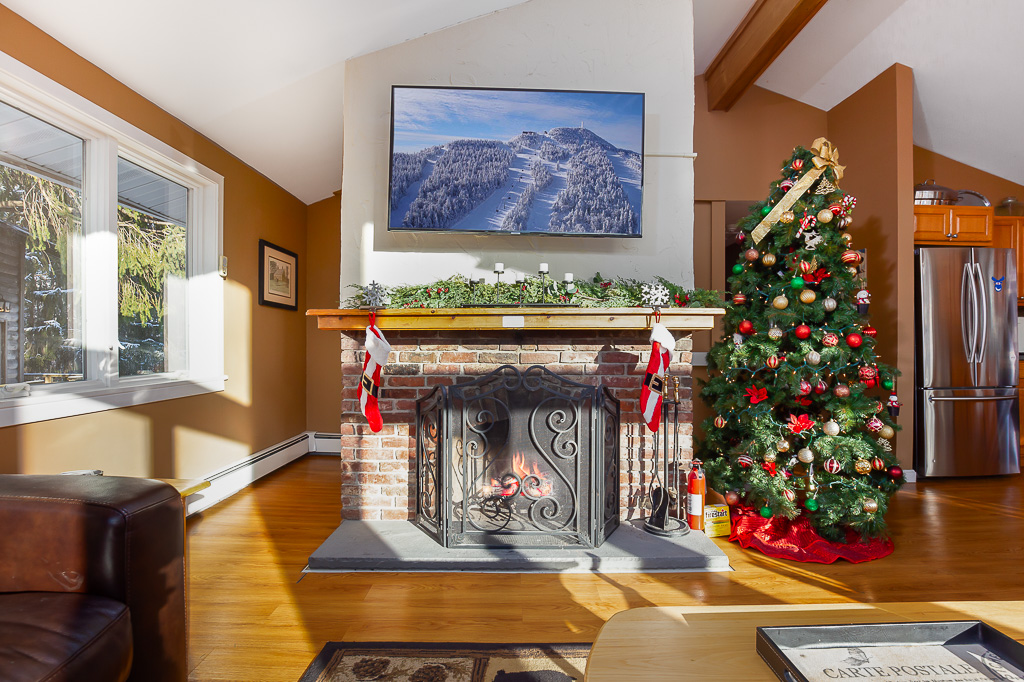Brick fireplace with mantel, stockings, and decorated Christmas tree