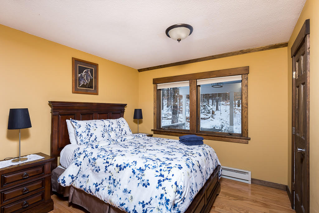 Yellow bedroom with floral blue bedding and snowy forest view