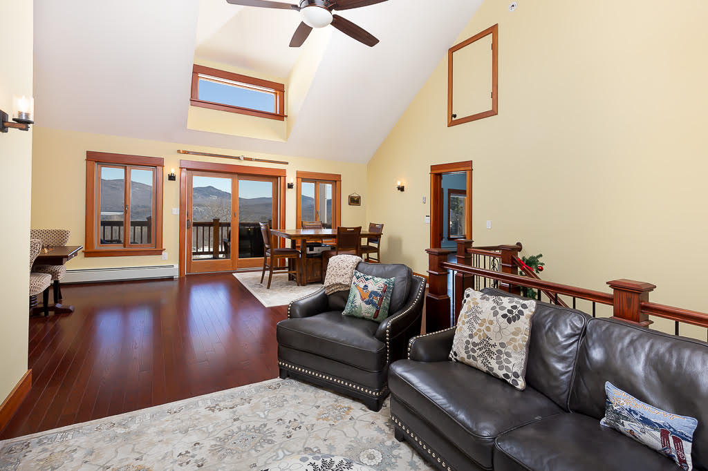 Great room with vaulted ceilings, leather seating, and mountain views through the deck doors