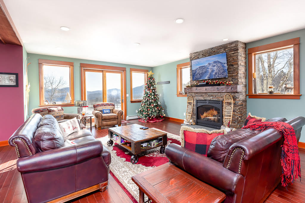 Living room with stacked-stone fireplace, mounted TV, and mountain-view windows