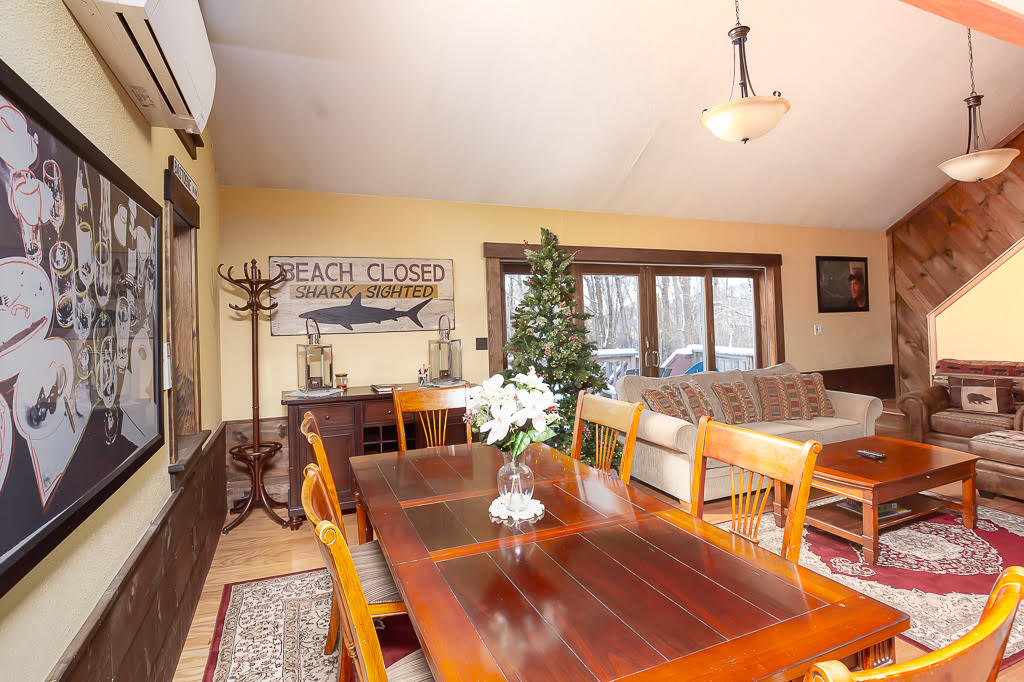 Dining area with wood table seating six and 'Beach Closed' wall art