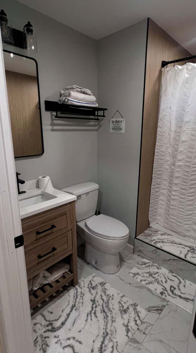 Modern gray bathroom with wood vanity, marble-tile floor, and walk-in shower