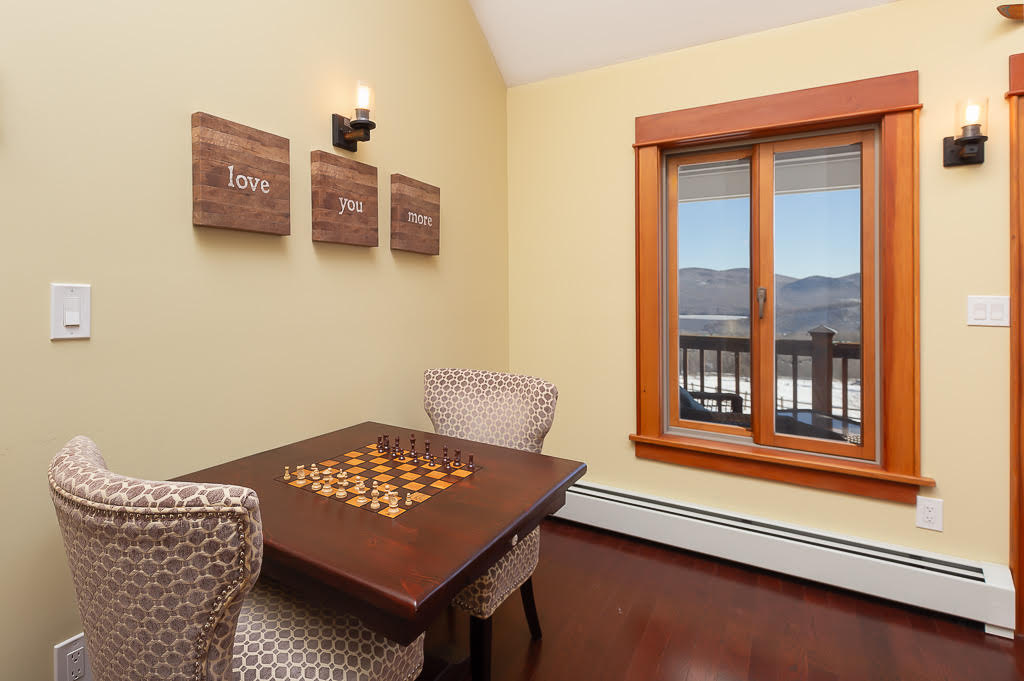 Cozy chess nook with 'love you more' wall art and mountain-view window