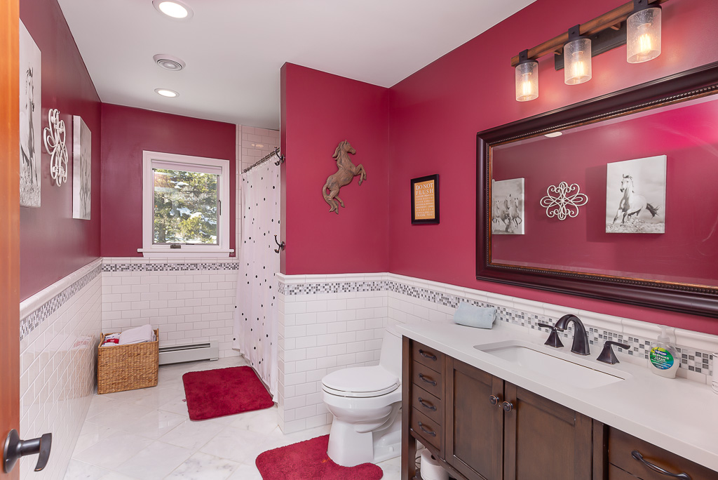 Pink horse-themed bathroom with subway tile wainscoting and dark wood vanity