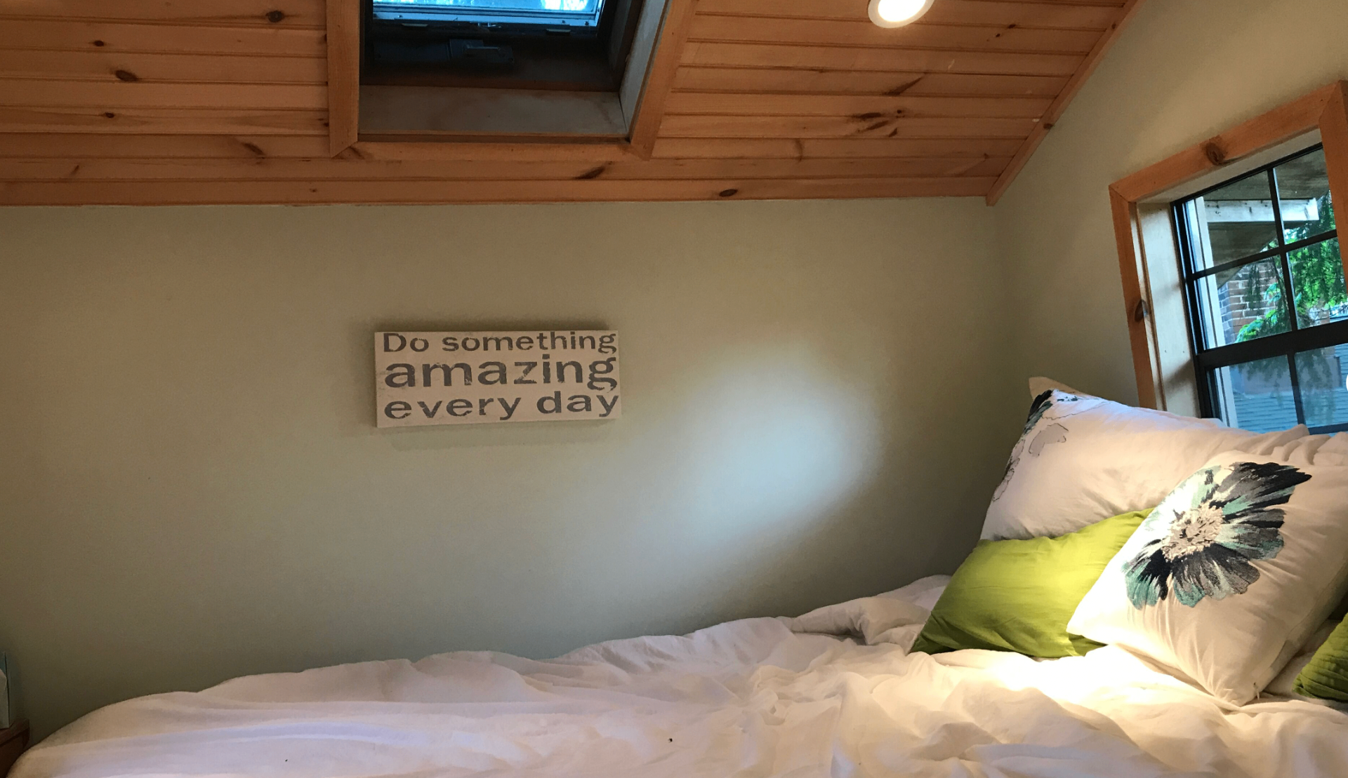 Treehouse loft bed with skylight and 'Do something amazing every day' sign