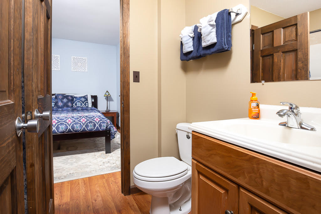 Bathroom with wood vanity and view into adjacent bedroom