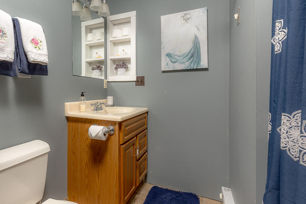 Gray bathroom with wood vanity, blue accents, and shower curtain