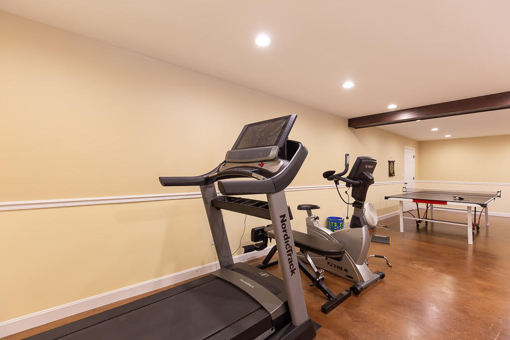 Home gym with NordicTrack treadmill, exercise bike, and ping pong table