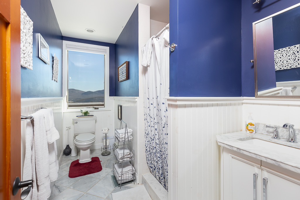 Blue and white guest bath with beadboard wainscoting and a mountain-view window