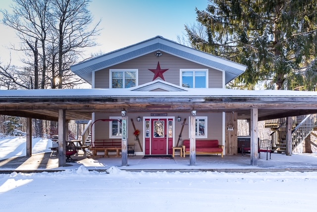 Front porch with red doors, vintage skis, and bench seating in winter