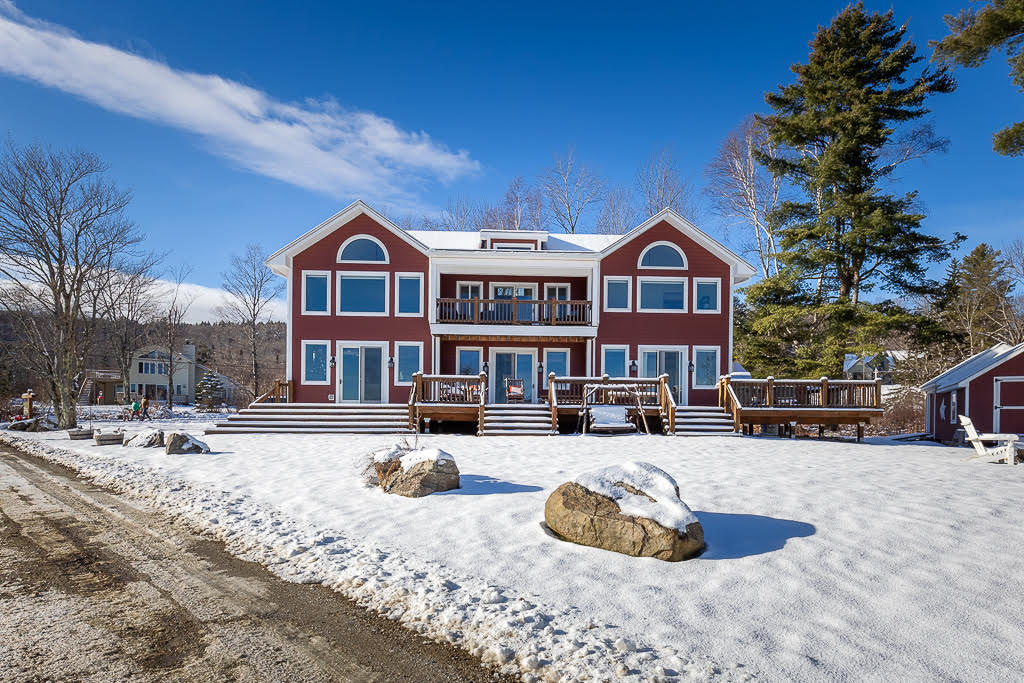 Rear of the lodge with wraparound deck and snowy meadow
