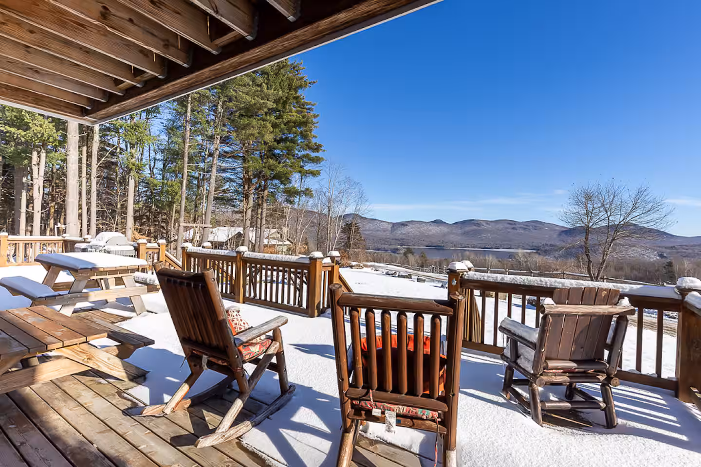 Snowy covered porch with log rocking chairs and panoramic winter mountain views
