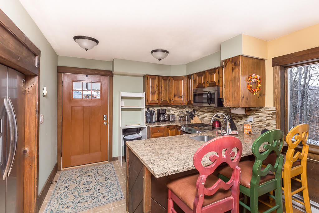 Kitchen entry with craftsman door, granite island, and tile floor