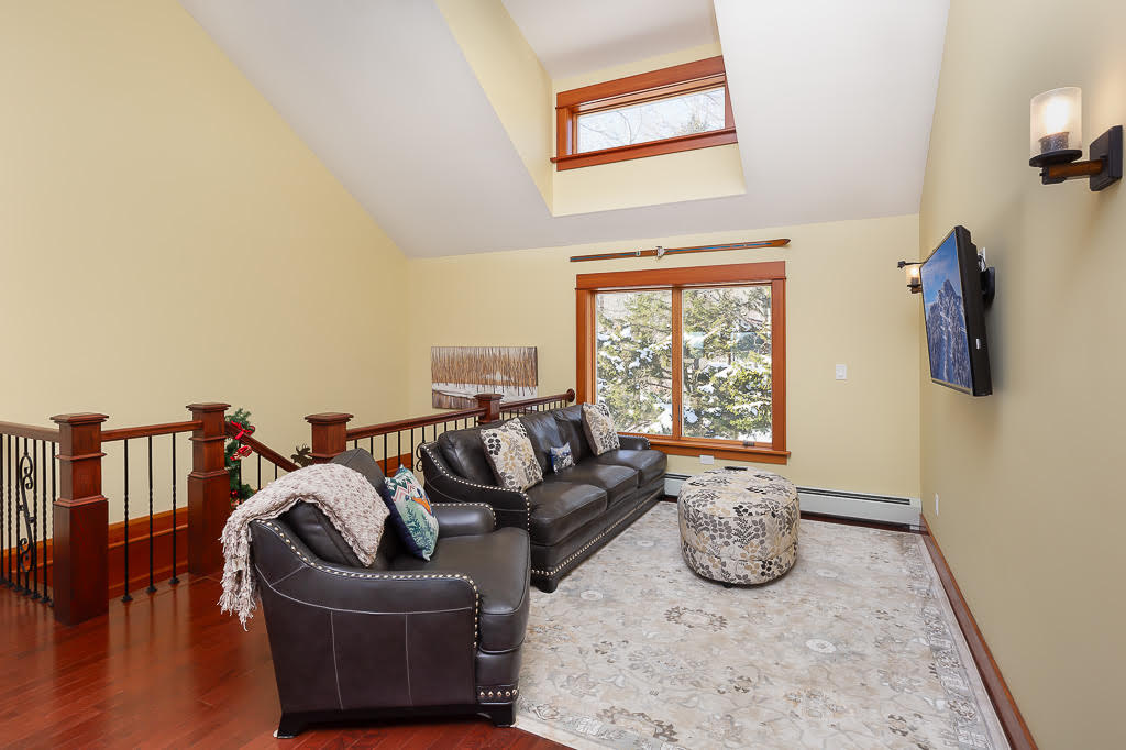 Upstairs lounge with leather sofas, vaulted ceiling, and mounted TV