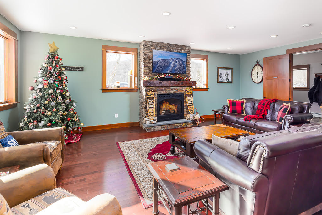 Living room with stone fireplace, leather sofas, and decorated Christmas tree