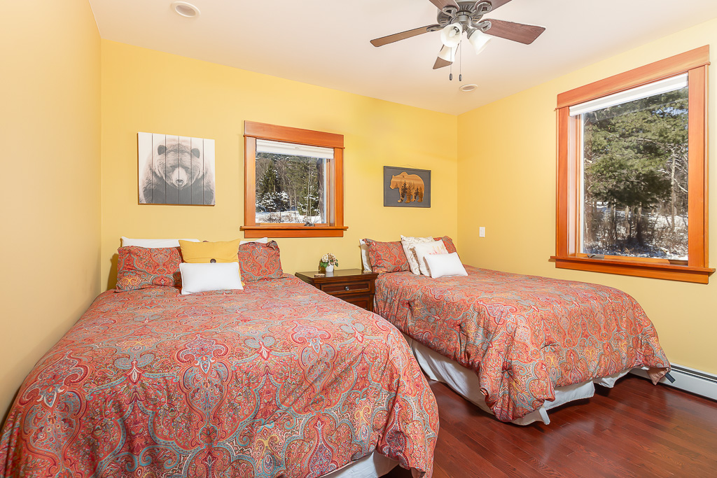 Yellow guest room with two paisley-covered beds and bear-themed wall art