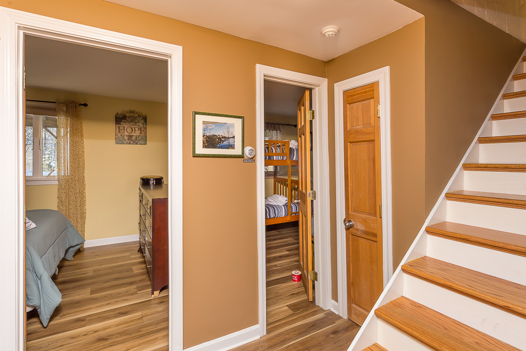 Upstairs hallway with bedroom and bunk-room doorways beside the staircase