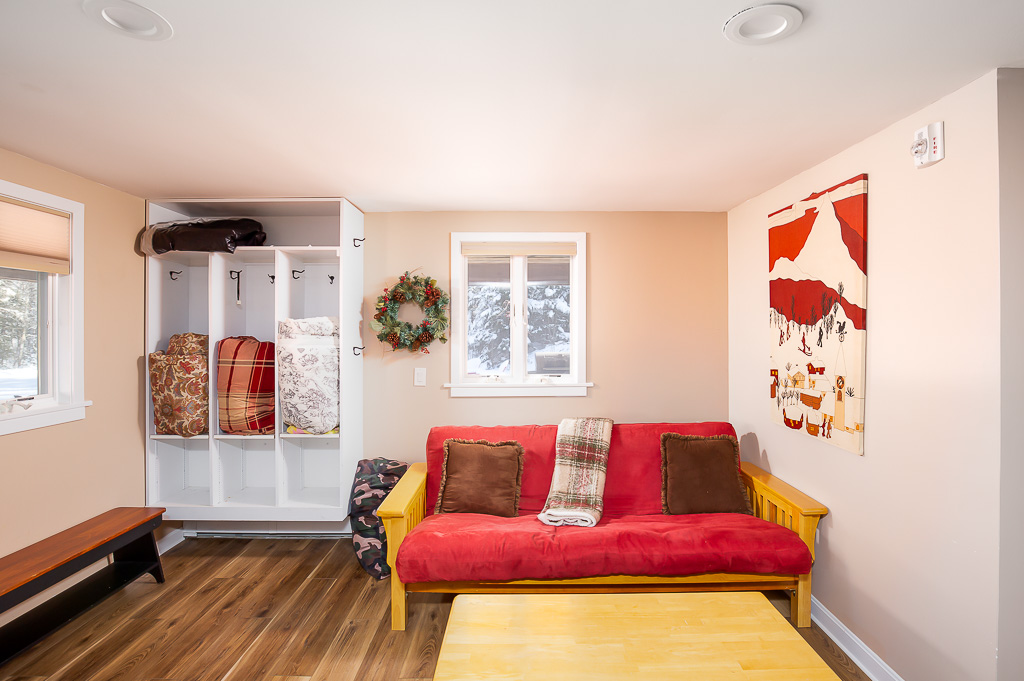 Mudroom with cubbies, red futon, and folk-art wall hanging