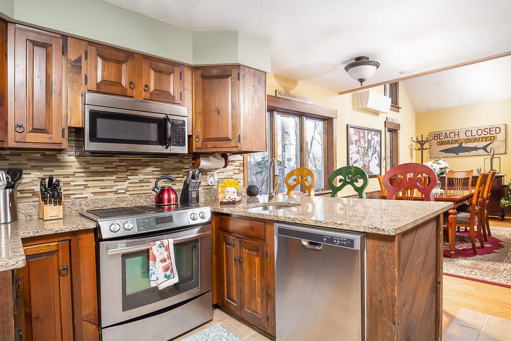 Kitchen with granite counters, stainless appliances, and colorful bar stools