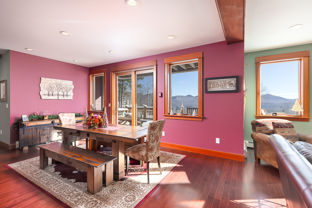 Dining room with pink accent wall, farmhouse table, and sliding doors to mountain-view deck