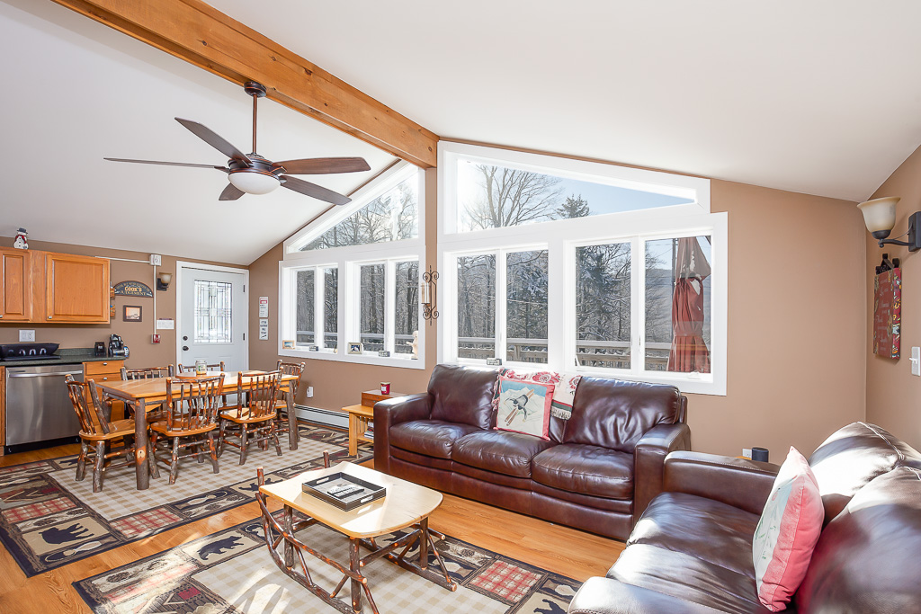 Open great room with vaulted ceilings, dining table, and mountain-view windows