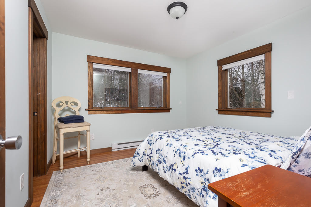 Light blue bedroom with floral bedding and large windows overlooking woods