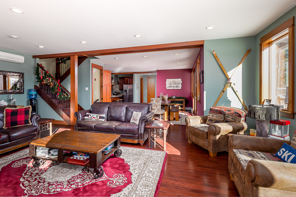 Open living area with leather sofas, vintage skis on the wall, and a red oriental rug
