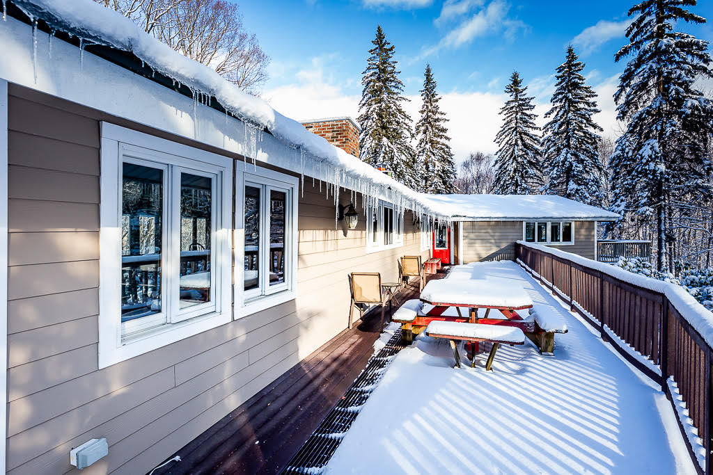 Snow-covered exterior deck with mountain pines at sunrise