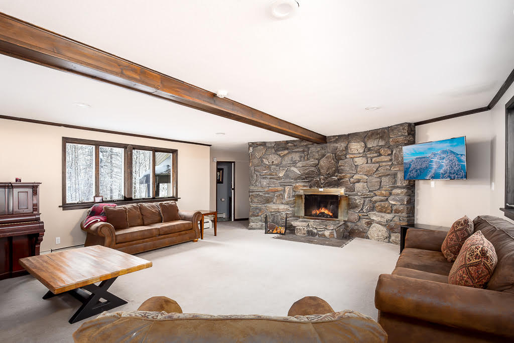 Spacious living room anchored by a floor-to-ceiling stone fireplace