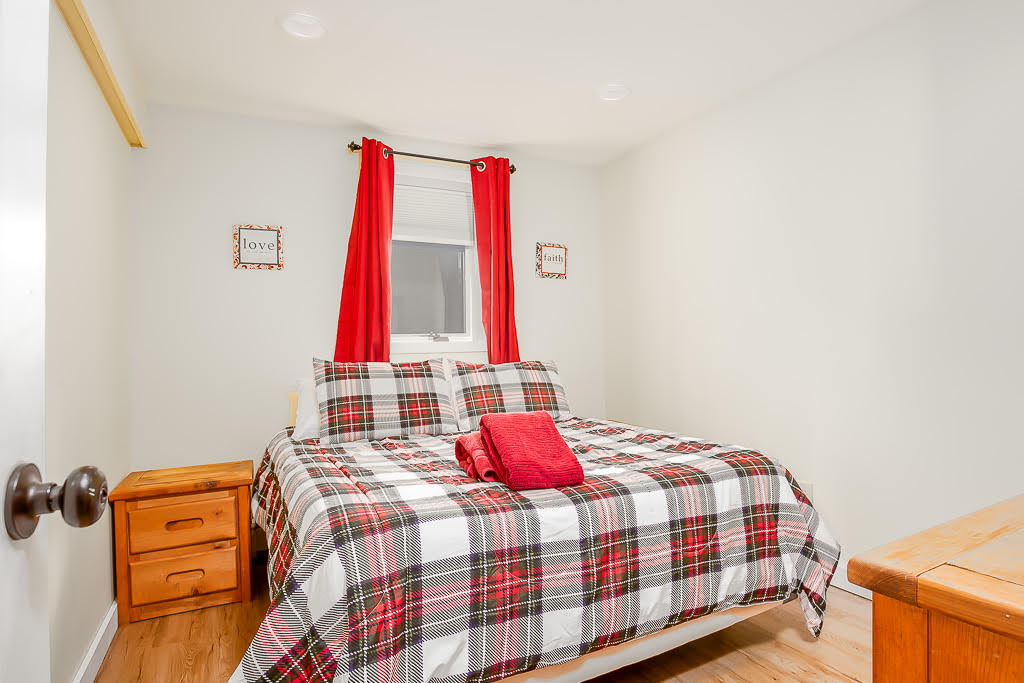Cozy bedroom with plaid linens and warm wood floors