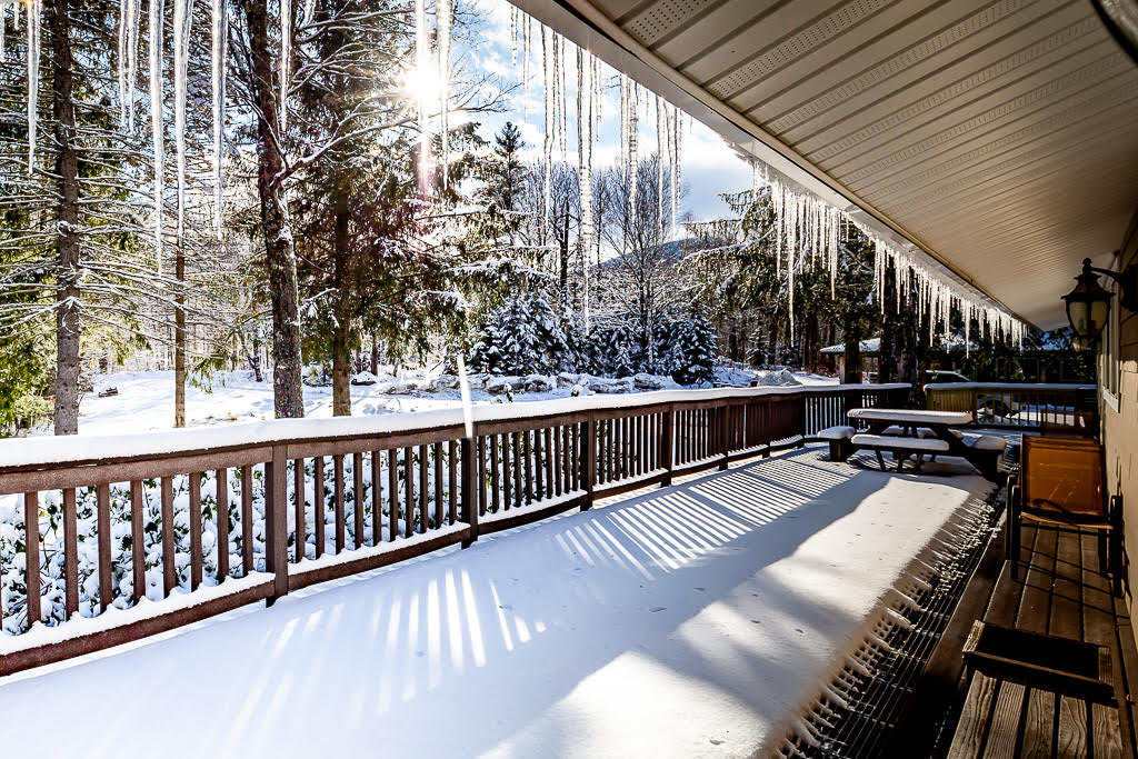 Wraparound deck blanketed in fresh snow with mountain views