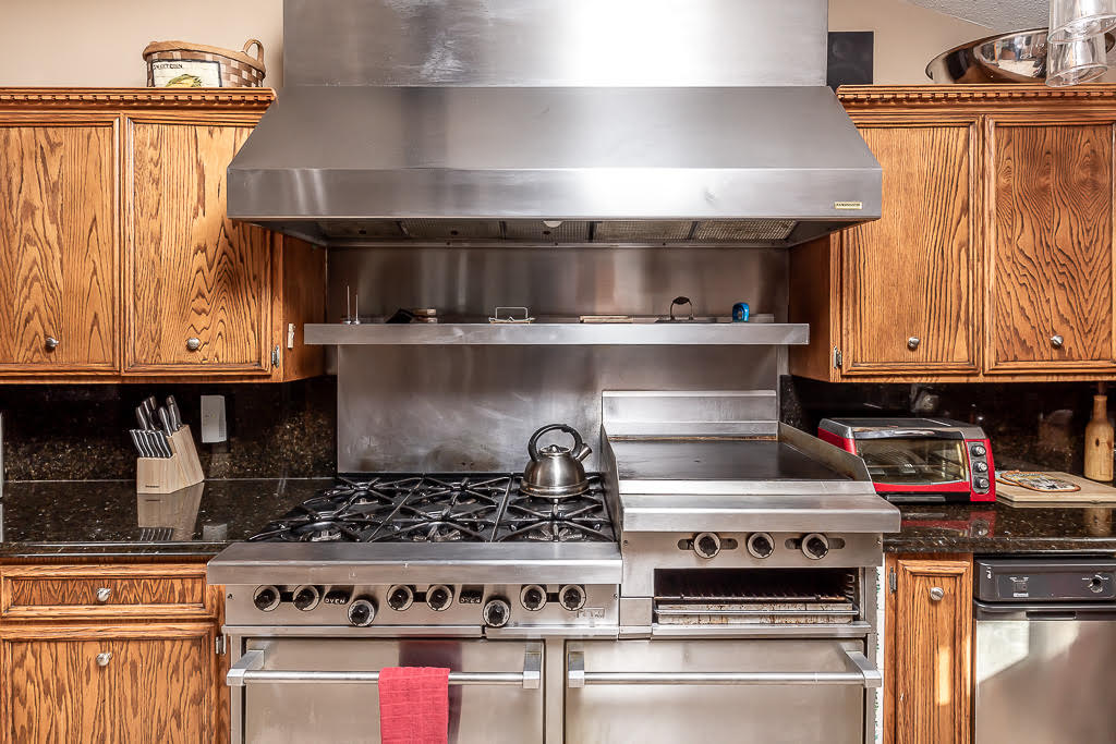Commercial-grade gas range and griddle under a stainless hood