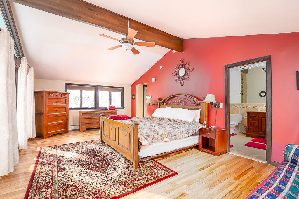 Primary suite with vaulted ceilings, hardwood floors, and en-suite bath