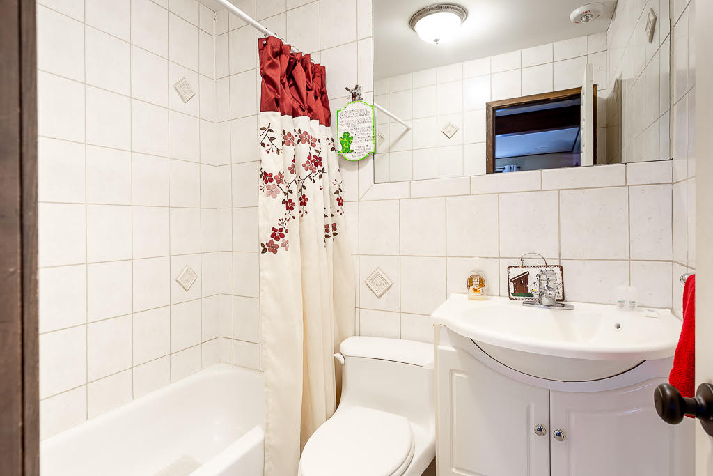 White-tiled bathroom with cherry-blossom shower curtain and vanity
