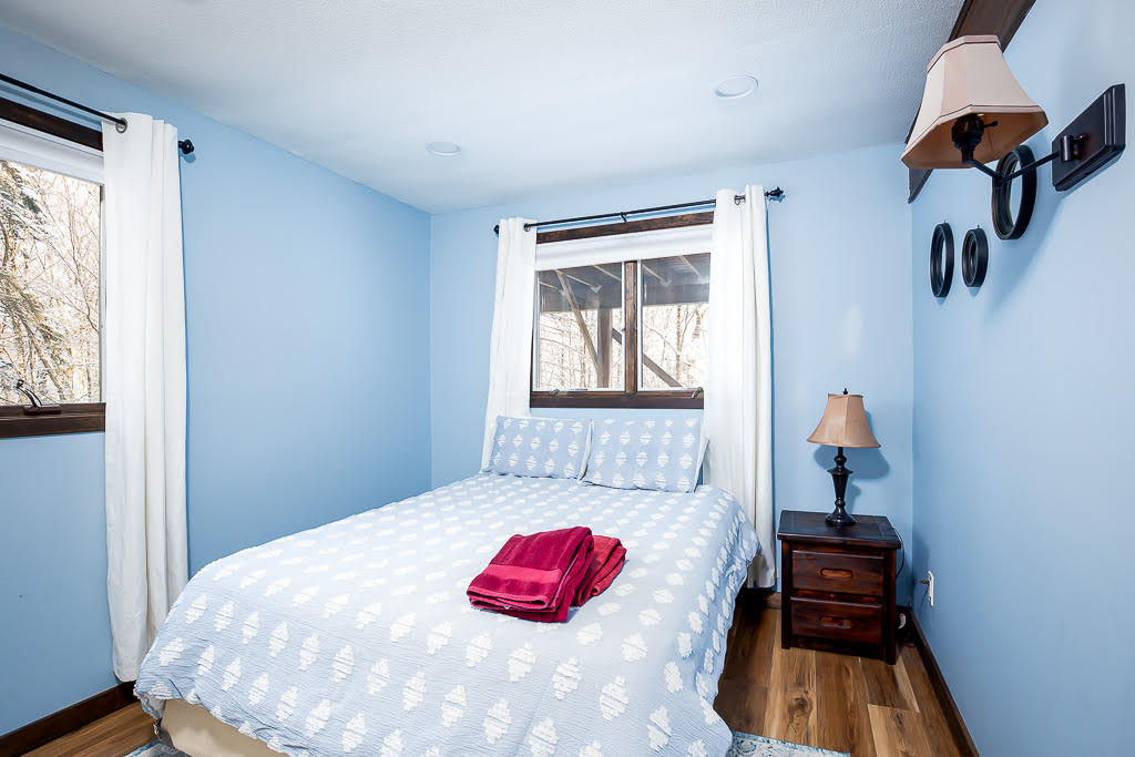 Sky-blue bedroom with queen bed and forest views through the windows