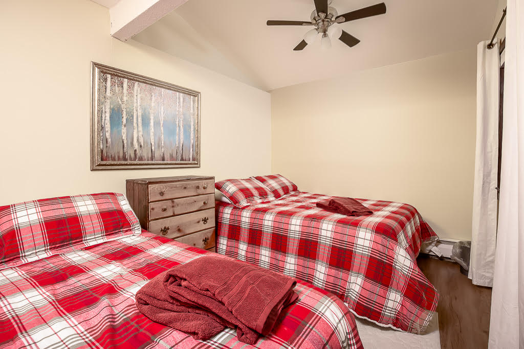 Vaulted bedroom with twin beds dressed in red plaid linens