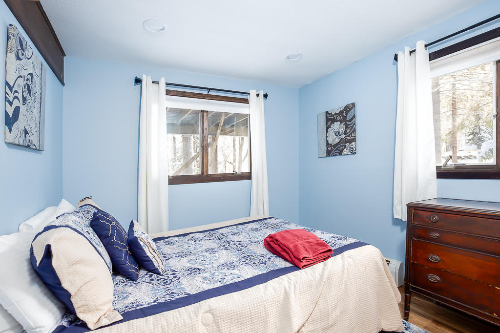 Blue-walled bedroom with framed artwork and antique dresser