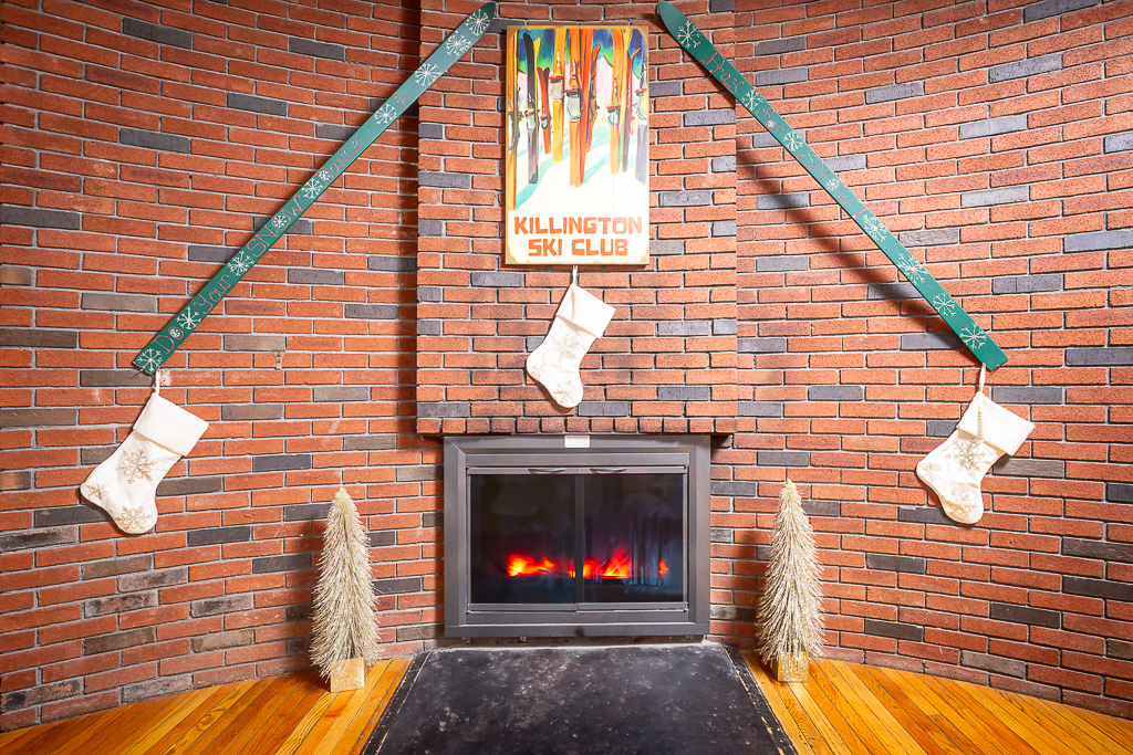 Brick fireplace flanked by vintage skis and Killington Ski Club sign with holiday stockings