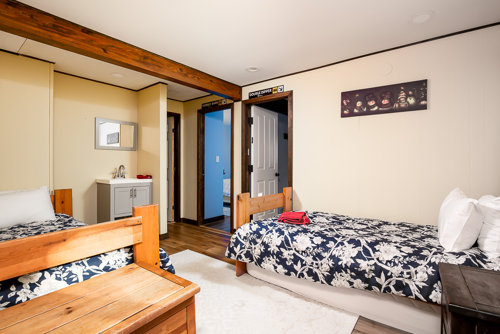Bunk room with twin beds, navy floral linens, and ski-trail-sign doorways