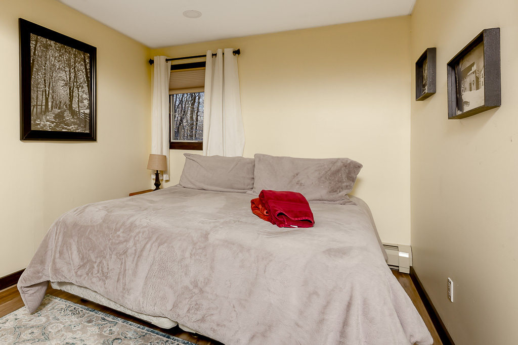 Cozy yellow bedroom with queen bed, plush bedding, and forest-view window