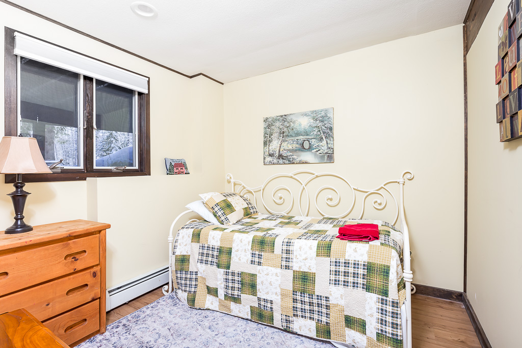 Bright bedroom with white iron daybed, patchwork quilt, and snowy window view